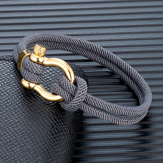 Pérignon Twist 
ein Armband wie ein Sommerabend am Hafen. Tauwerk und Goldschließe treffen auf den Luxus eines Champagner-Moments. Am besten getragen zum offenen Leinenhemd von Ralph Lauren – ein Detail, das nicht jeder versteht, aber die Richtigen.