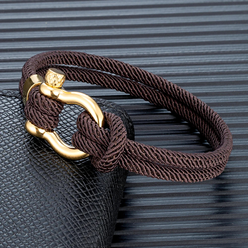Pérignon Twist 
ein Armband wie ein Sommerabend am Hafen. Tauwerk und Goldschließe treffen auf den Luxus eines Champagner-Moments. Am besten getragen zum offenen Leinenhemd von Ralph Lauren – ein Detail, das nicht jeder versteht, aber die Richtigen.