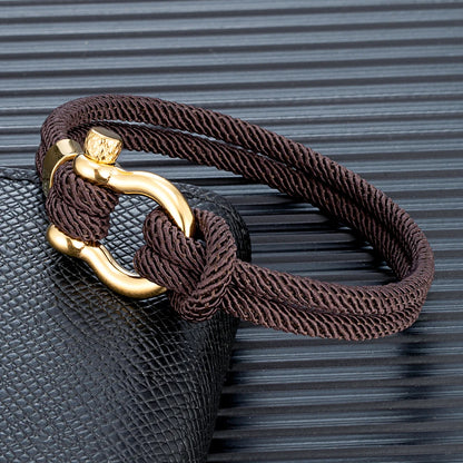 Pérignon Twist 
ein Armband wie ein Sommerabend am Hafen. Tauwerk und Goldschließe treffen auf den Luxus eines Champagner-Moments. Am besten getragen zum offenen Leinenhemd von Ralph Lauren – ein Detail, das nicht jeder versteht, aber die Richtigen.