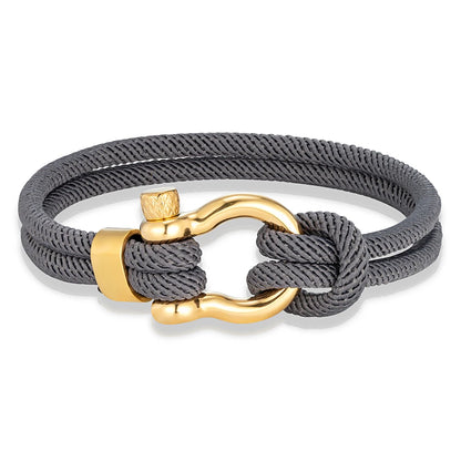 Pérignon Twist 
ein Armband wie ein Sommerabend am Hafen. Tauwerk und Goldschließe treffen auf den Luxus eines Champagner-Moments. Am besten getragen zum offenen Leinenhemd von Ralph Lauren – ein Detail, das nicht jeder versteht, aber die Richtigen.